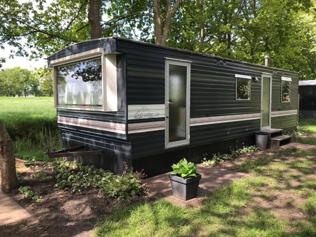 a black tiny house sitting in a yard at Evenrust, gelegen nabij het Pieterpad in Coevorden