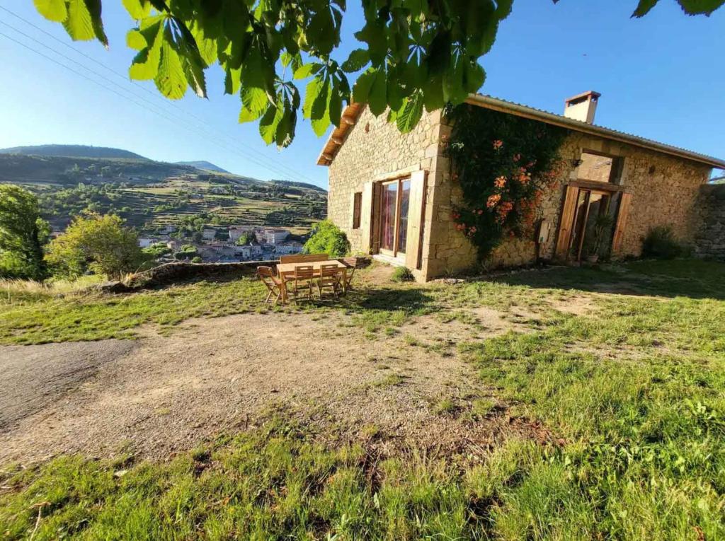 uma casa de pedra com uma mesa de piquenique num campo em Le Grenier à Blé em Satillieu