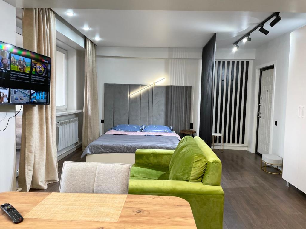 ein Schlafzimmer mit einem Bett und einem grünen Sofa in der Unterkunft Apartment on KShT in Öskemen