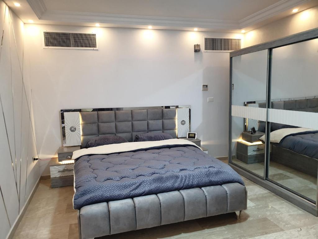 1 dormitorio con 1 cama grande y espejo grande en Deir Ghbar-Studio en Amán