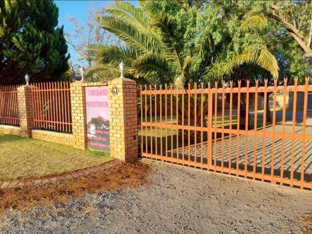 a wooden fence with a sign on it at Chrisand Guesthouse in Kuruman