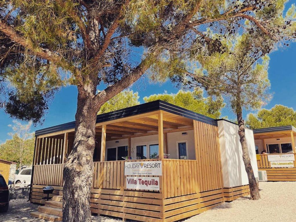 drewniany budynek z drzewem przed nim w obiekcie 3V Holiday Resort w mieście Drage