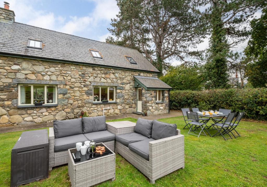 a patio with a couch and a table in front of a stone house at Cil y Fan in Llangelynin