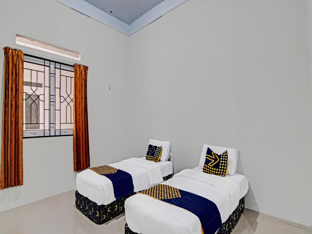 2 Betten in einem Zimmer mit Fenster in der Unterkunft OYO 91847 Rumah Singgah Kinaya Syariah in Parit