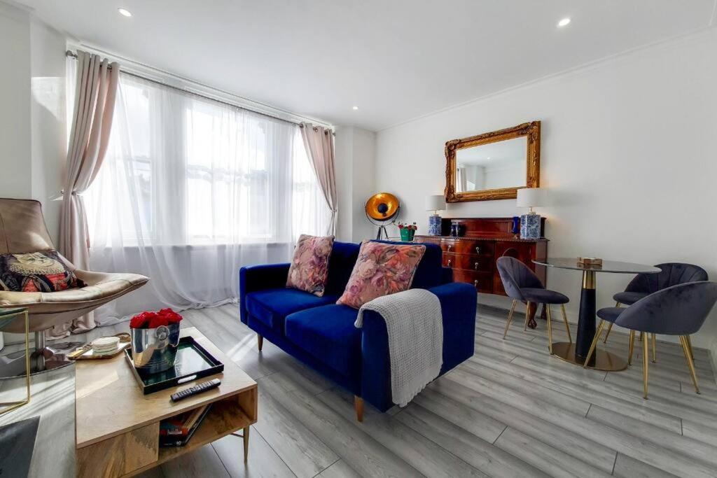 uma sala de estar com um sofá azul e uma mesa em Immaculately presented 1 bed em Londres