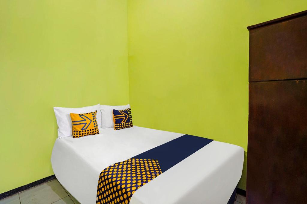 Cama en habitación con paredes verdes en OYO Life 91869 Insan Mulia Kost Syariah, en Mojokerto