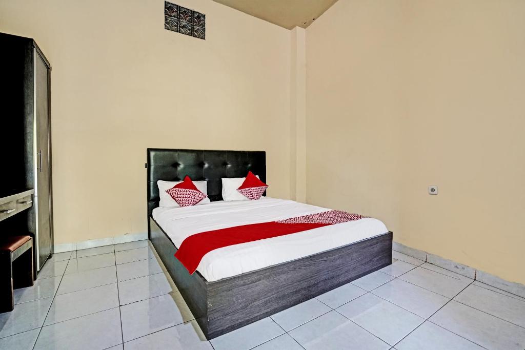 1 dormitorio con 1 cama con almohadas rojas y blancas en OYO Life 91873 Nugraha Kost, en Palembang