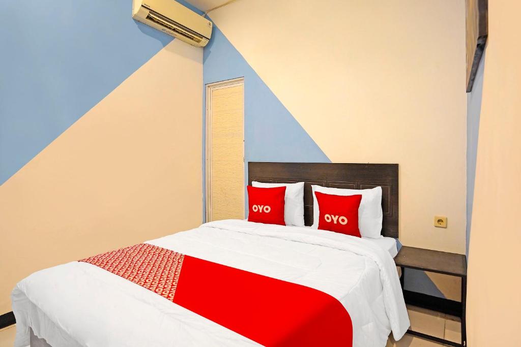 a bedroom with a red and white bed with two red pillows at OYO 91867 Gangnam Style Kutai in Surabaya
