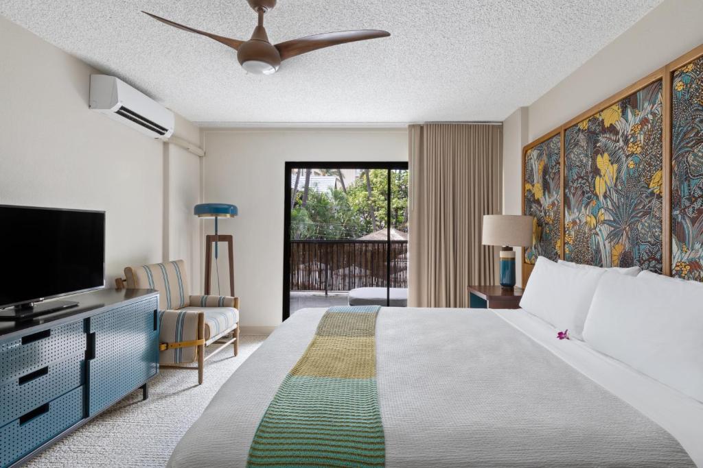 a bedroom with a large bed and a tv at White Sands Hotel in Honolulu