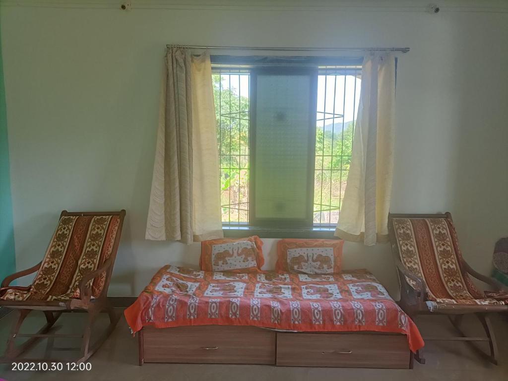 a bedroom with a bed and two chairs and a window at Basant - Madhu in Alibaug