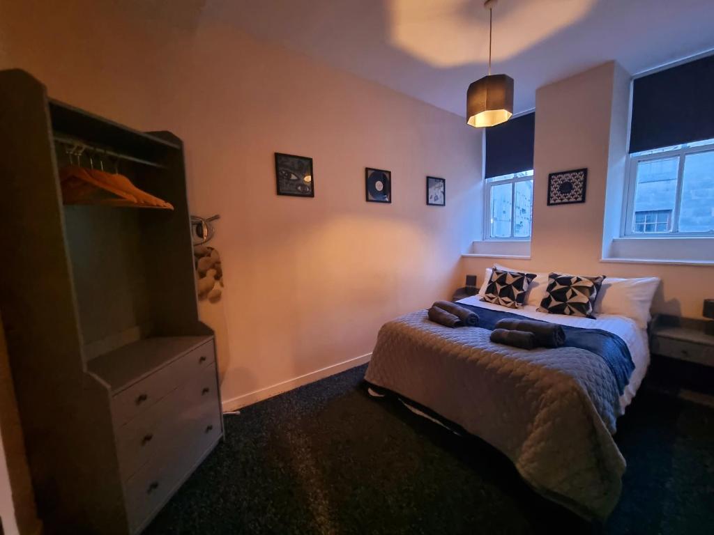 a bedroom with a bed and a dresser and windows at Nicky-Tams Bar & Apartments in Stirling