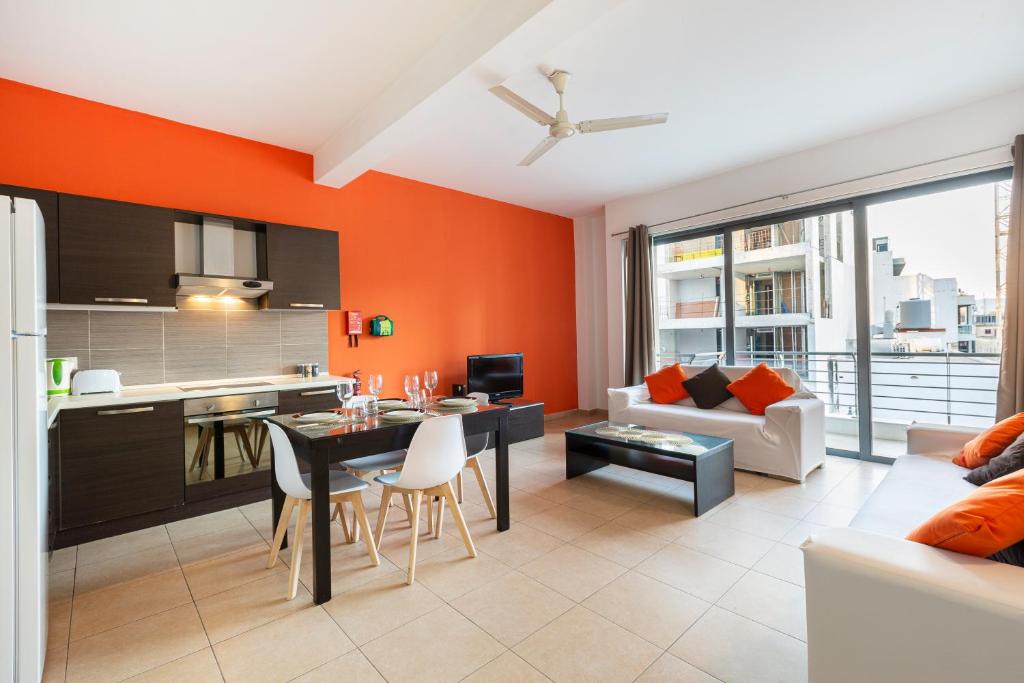 a kitchen and living room with an orange wall at Roulette Your St Julians Base for a Fun Getaway in Paceville