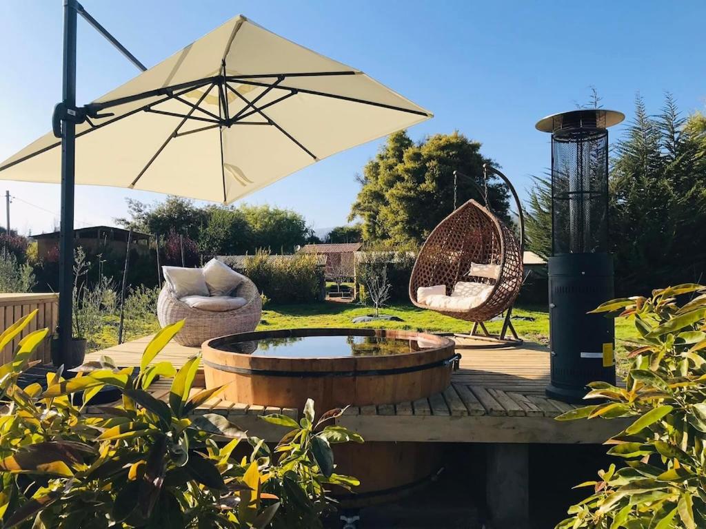 un patio con sombrilla, silla y columpio en Encantadora Casa del Árbol en el Valle del Elqui!, en La Serena