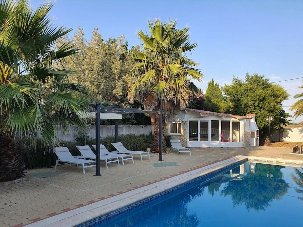 einen Pool mit Stühlen und einen Pavillon neben einem Haus in der Unterkunft Villa Flamants Rose in Marseillan