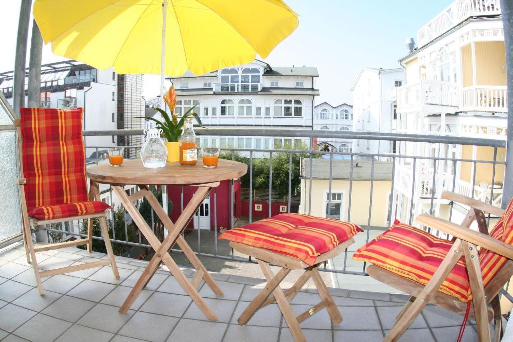 einen Balkon mit einem Tisch, Stühlen und einem gelben Regenschirm in der Unterkunft Salzinsel Binz in Binz