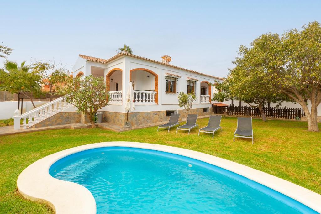 a villa with a swimming pool in front of a house at Casa Guadalmar in Málaga