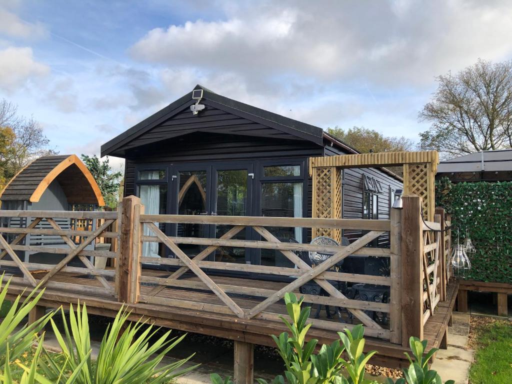 a black house with a wooden fence around it at Peaceful Holiday Lodge with Hot Tub in Lincolnshire