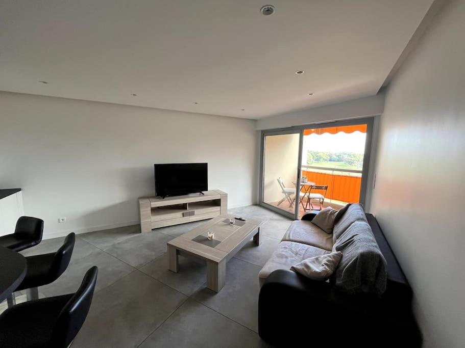 a living room with a couch and a tv and a table at Appartement 2 pièces vue mer, à proximité de tout in Mandelieu-la-Napoule