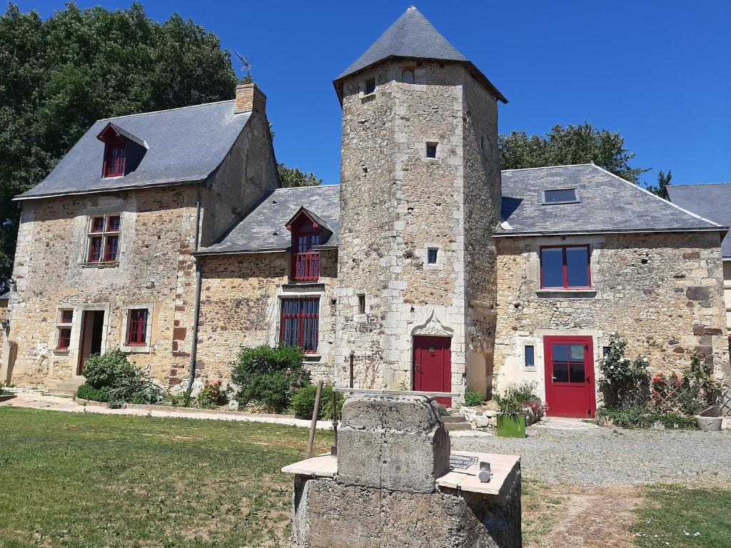 un antiguo edificio de piedra con una torre con puertas rojas en MANOIR AU CALME 10 KM DU MANS en Fay