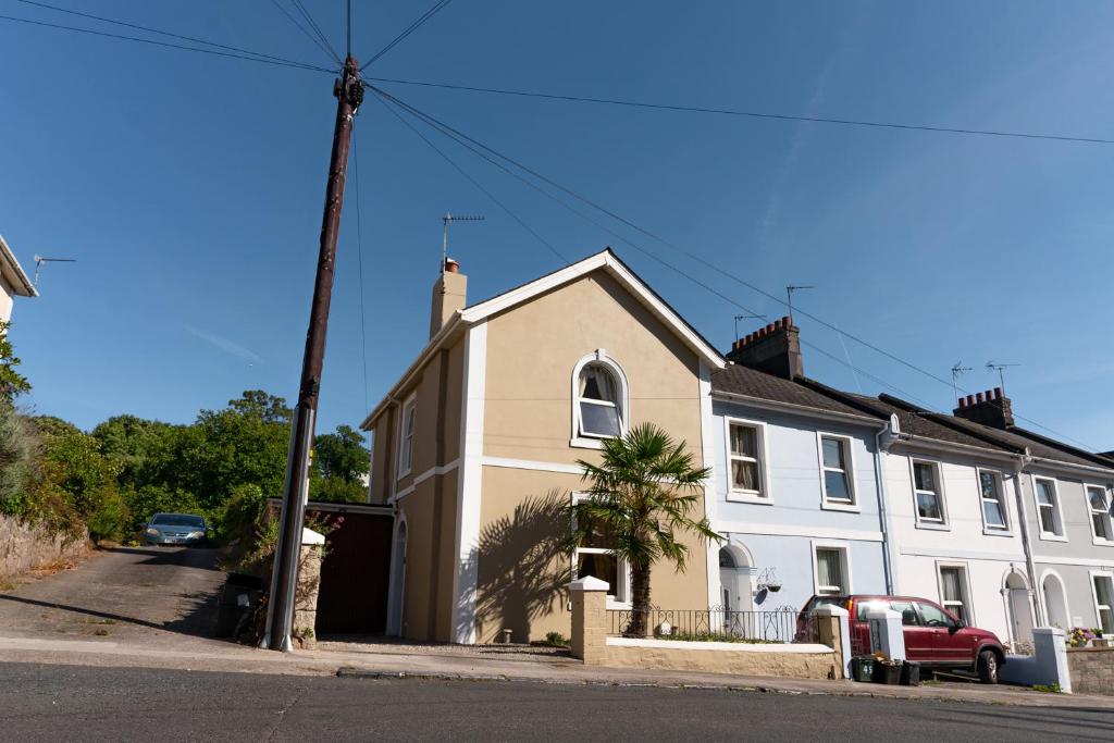 uma casa branca com um carro vermelho estacionado em frente dela em Upton House - Charming 4-bedroom home in Torquay em Torquay
