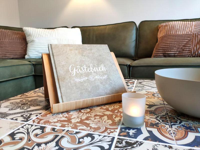 a living room with a book and a candle on a coffee table at Ferienhaus Blaue Blume mit 11 kW Ladestation, Kamin, Terrasse, eingezäuntem Garten, Sauna, WLAN, Netflix, 2 Hunde willkommen! in Güntersberge