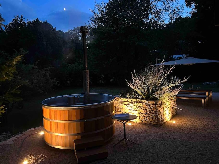 a wooden barrel with a fountain in a yard with a bench at Unique Sustainabel Lodge in the Swiss Jura Mountains in Neuchâtel