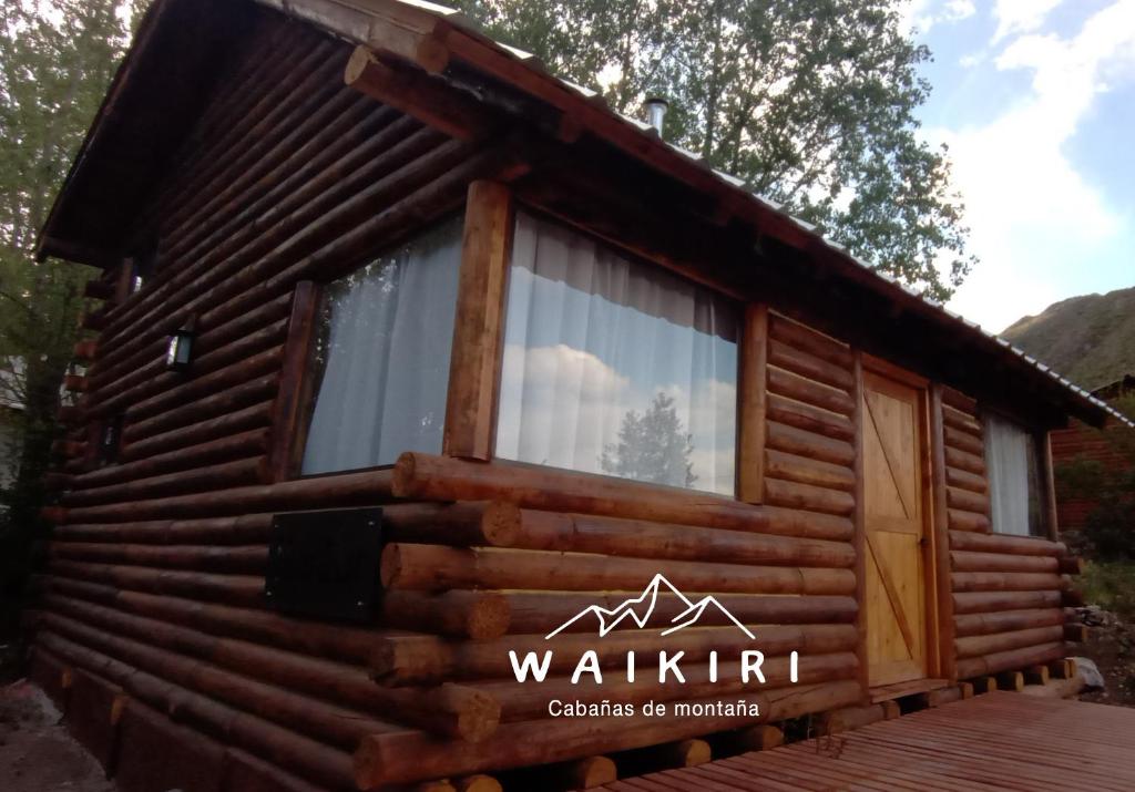 eine Blockhütte mit einem Fenster auf einem Deck in der Unterkunft WAIKIRI in Potrerillos