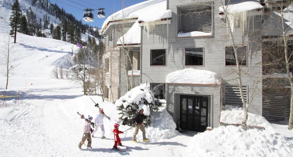 a group of people standing in the snow in front of a house at Palisades Tahoe Lodge in Olympic Valley