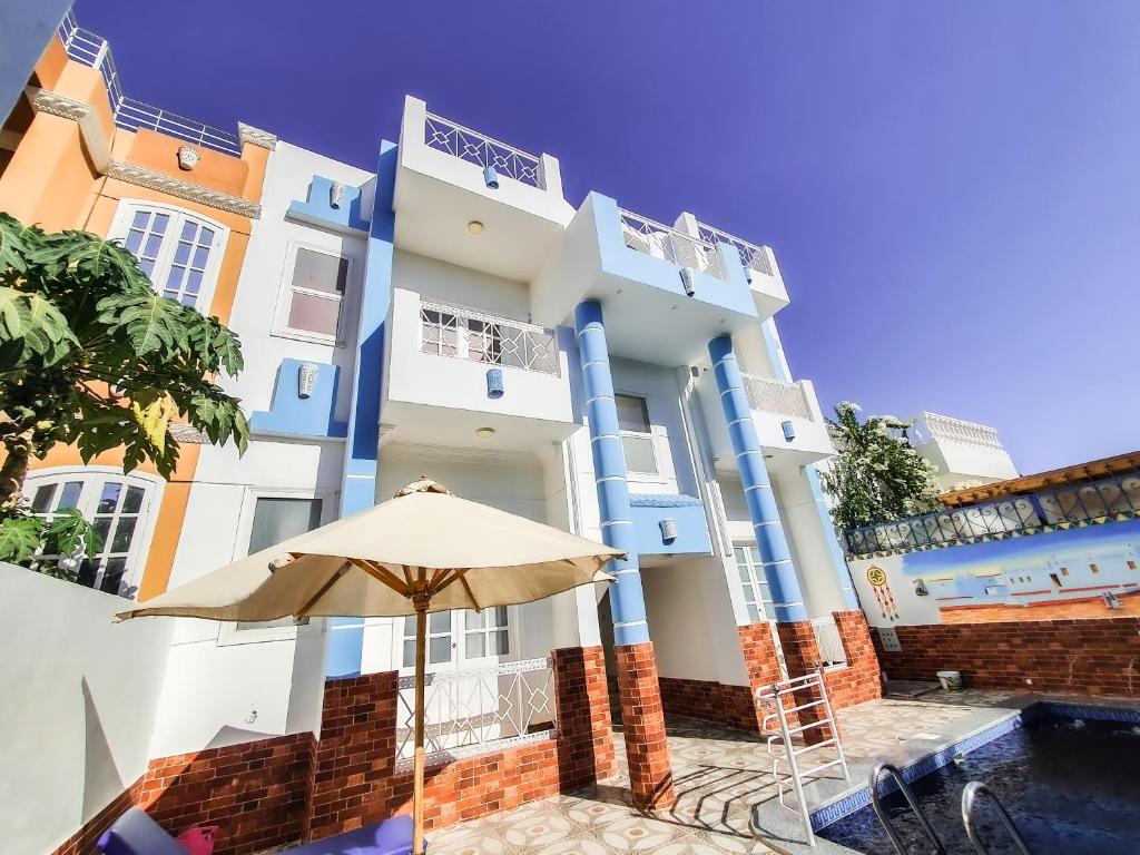 盧克索的住宿－Sunshine House，蓝白色的建筑,带雨伞