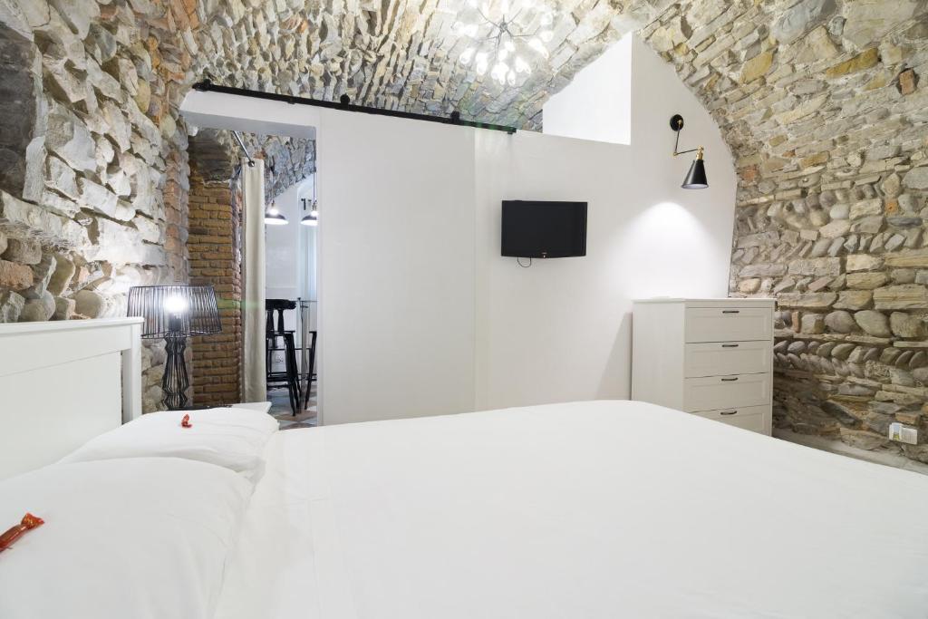 a bedroom with a white bed and a stone wall at BERGAMO art in Bergamo