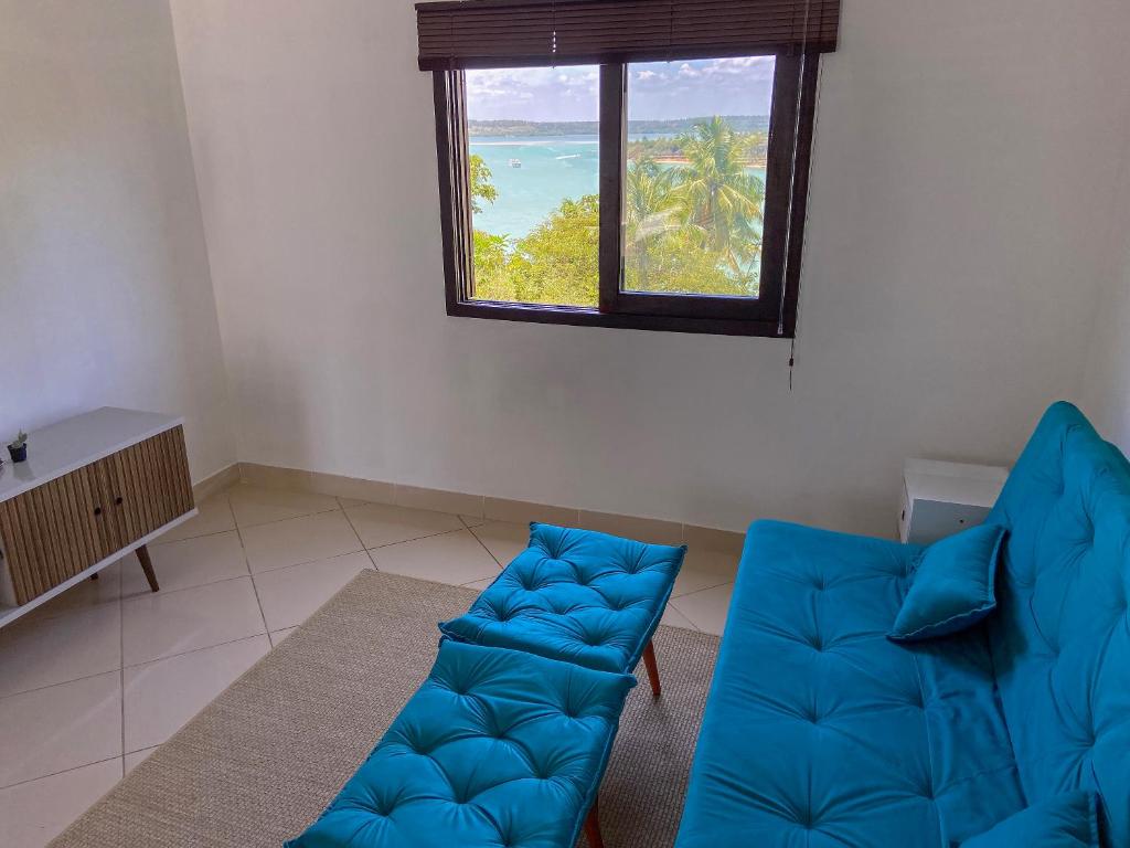 a living room with a blue couch and a window at Apto no centro de Tibau com vista para lagoa/mar in Pipa