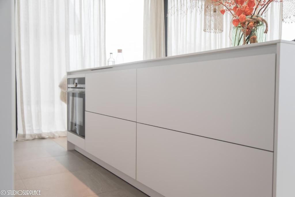 a kitchen with white cabinets and a window at La Naturale Garden zeezicht in Zeebrugge