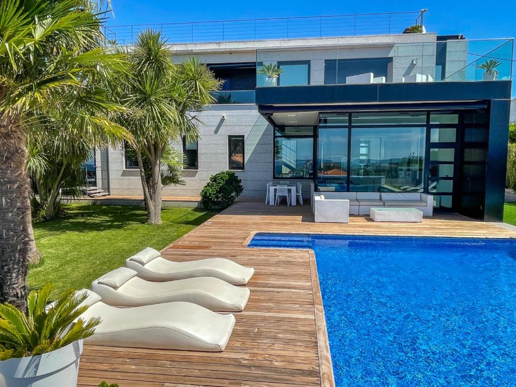 a house with a swimming pool in front of a house at Lujosa villa vistas al mar y piscina climatiza in Sanxenxo