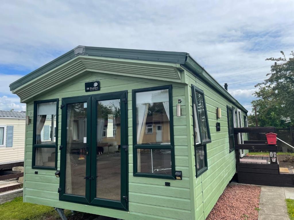 a green tiny house with a pitched roof at 2-Bedroom Parkhome in Uddingston, Glasgow in Uddingston