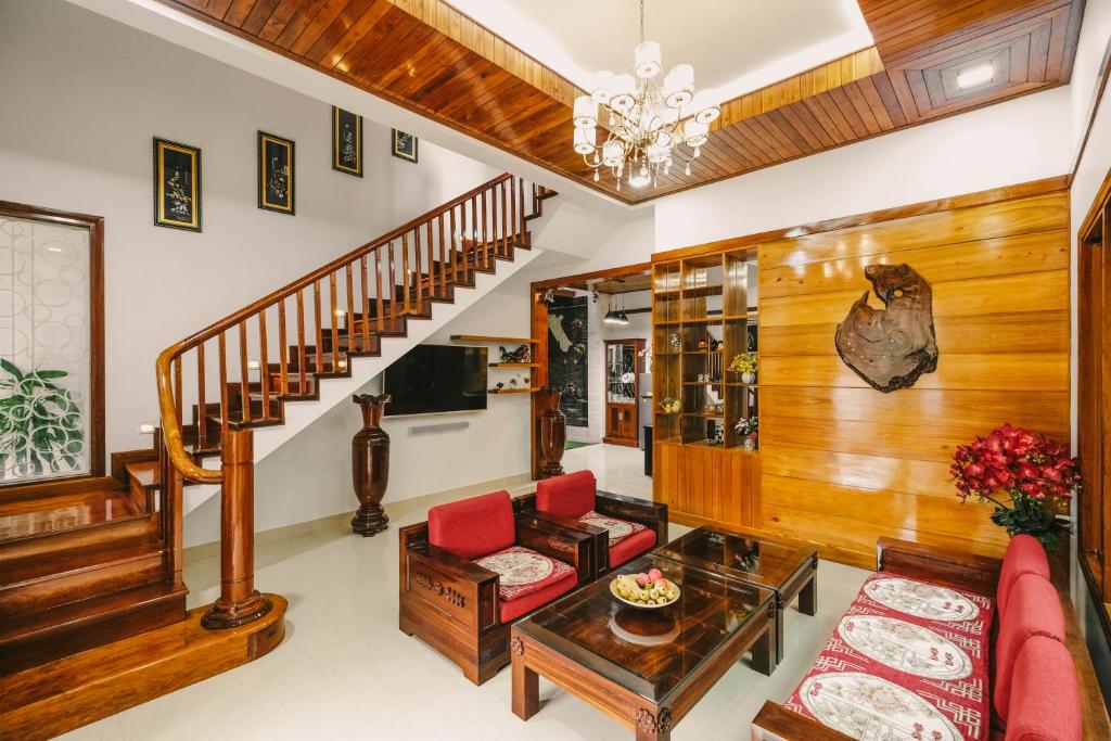 a living room with a staircase and red chairs at Le Robinet Villa - a journey into Hue citadel soul in Hue