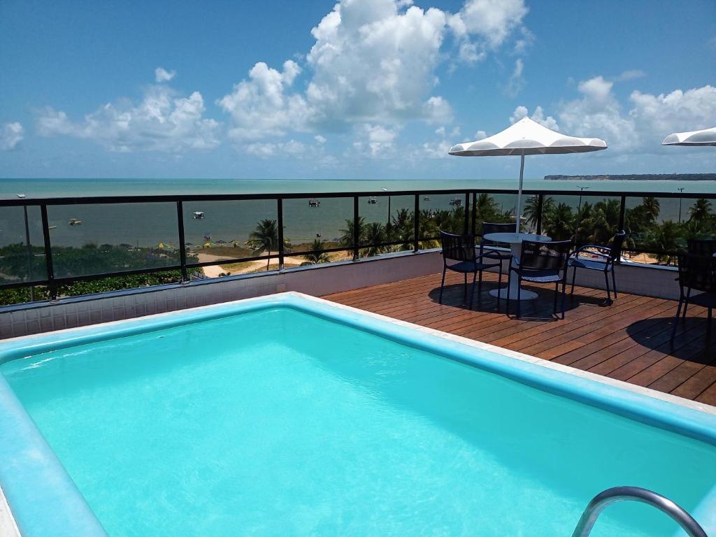 a swimming pool on a balcony with a table and umbrella at Flat pé na areia Tambaú in João Pessoa