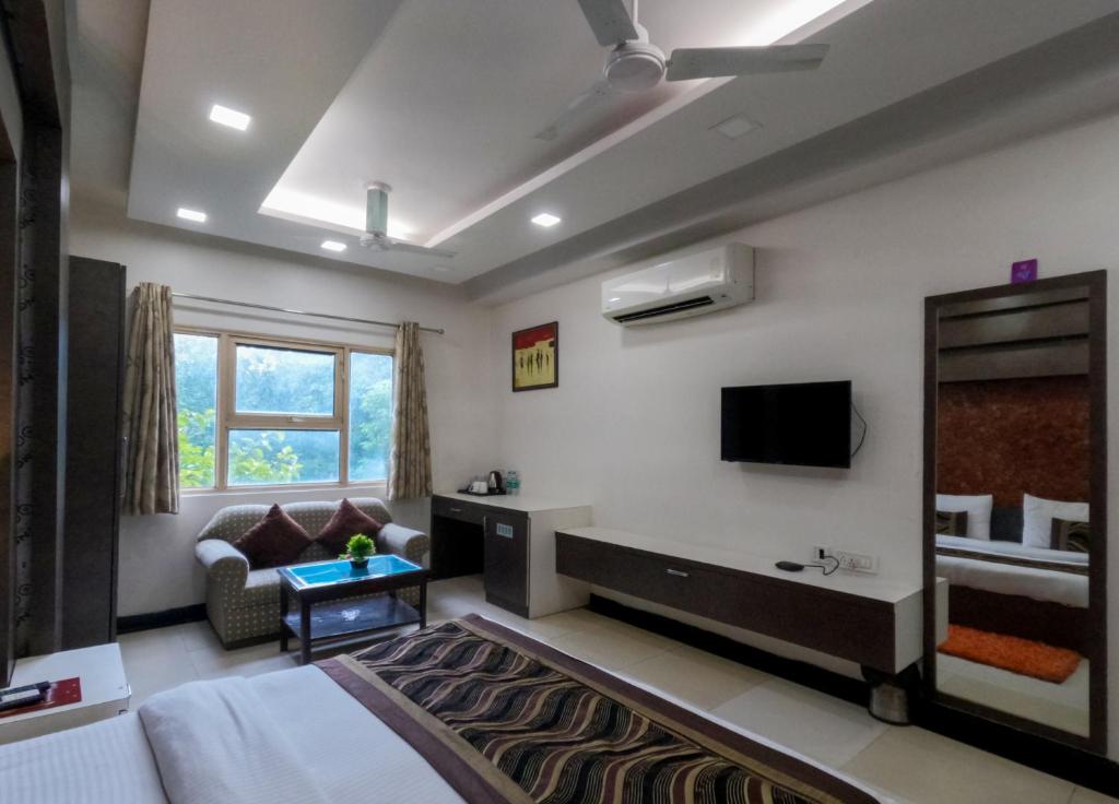 a bedroom with a bed and a tv and a couch at Hotel Red Castle - Karol Bagh in New Delhi