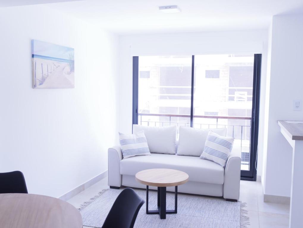 ein Wohnzimmer mit einem weißen Sofa und einem Tisch in der Unterkunft C(2) Precioso y cómodo departamento a metros del mar in Mar del Plata