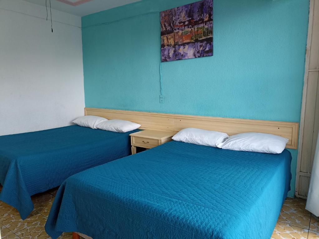 2 camas en una habitación con paredes azules en Hotel Viena, en Irapuato