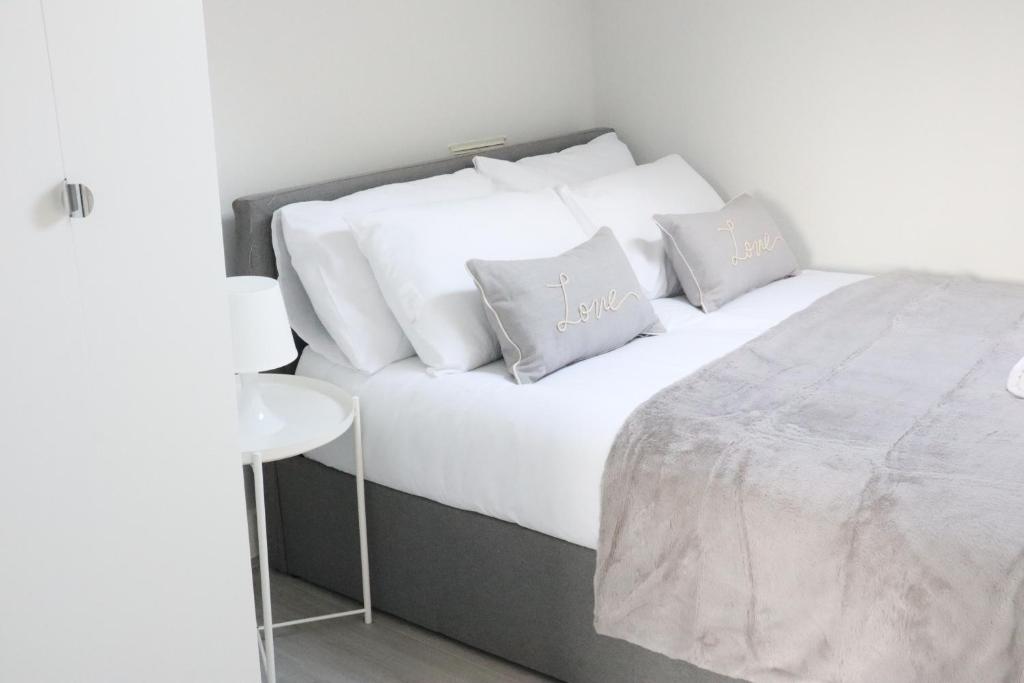 a bedroom with a bed with white sheets and pillows at Twelve Thirty Serviced Apartments - 1 Croydon in South Norwood