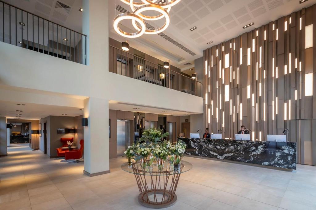 a lobby with a reception desk and flowers on a table at Clayton Hotel Manchester City Centre in Manchester