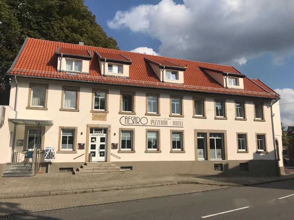 un grand bâtiment blanc avec un toit rouge dans l'établissement CAESARO Hotel & Pizzeria - 20 Jahre Familienunternehmen, à Hagen