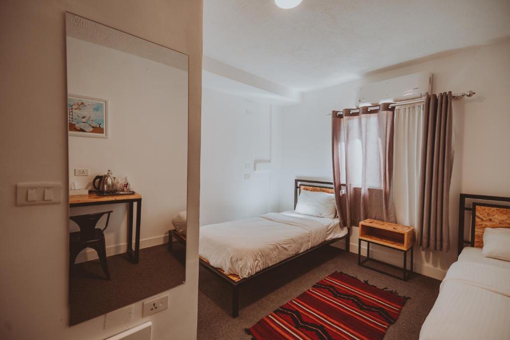 einen Spiegel in einem kleinen Zimmer mit einem Bett und einem Schreibtisch in der Unterkunft Nomads Hotel Petra in Wadi Musa