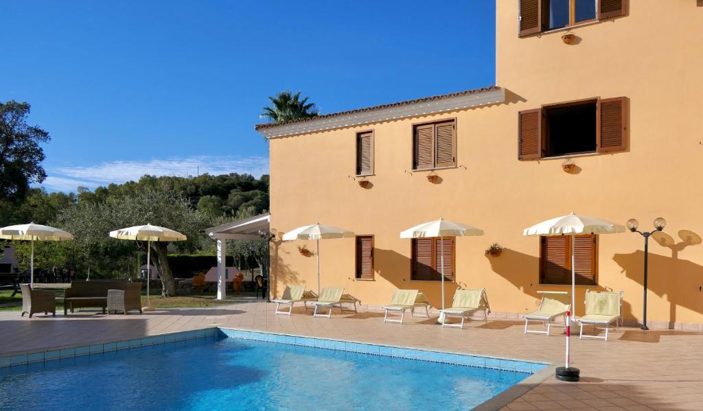 um edifício com piscina, cadeiras e guarda-sóis em Residence con piscina a Sos Alinos em Cala Liberotto