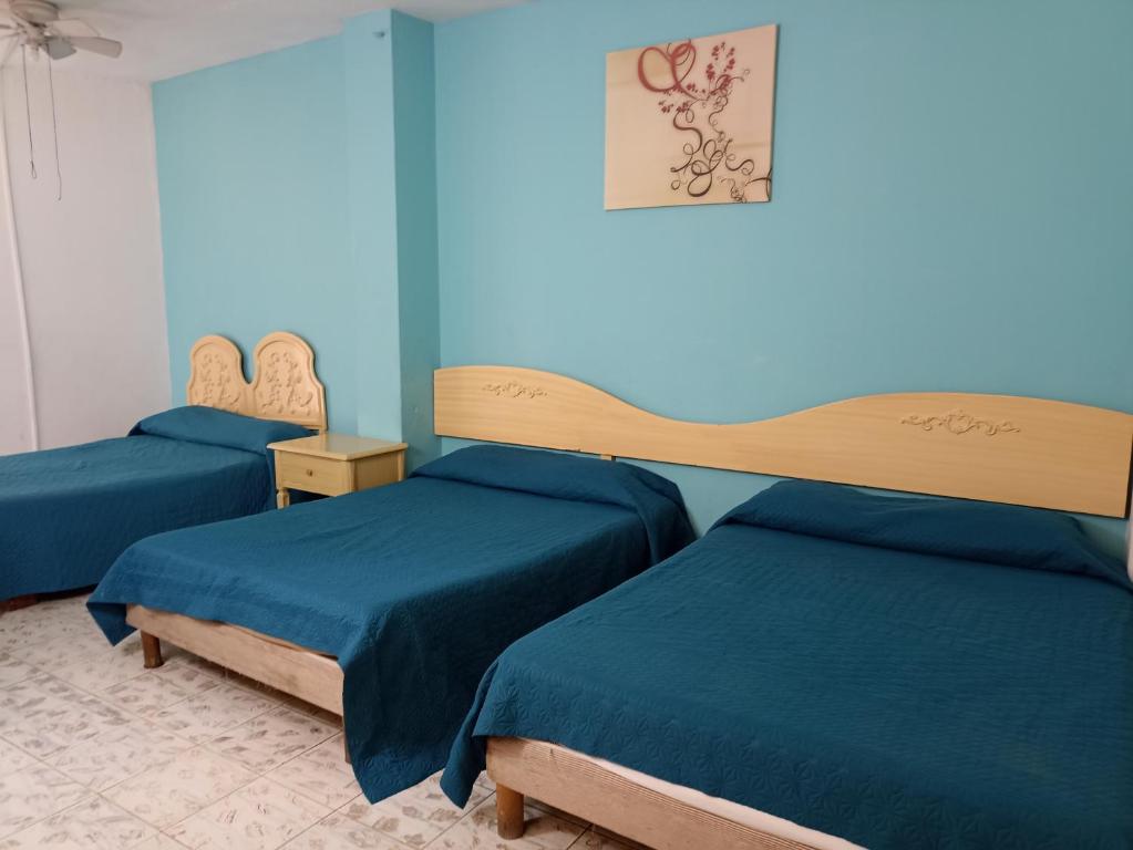 2 camas en una habitación con paredes azules en Hotel San Carlos, en Irapuato