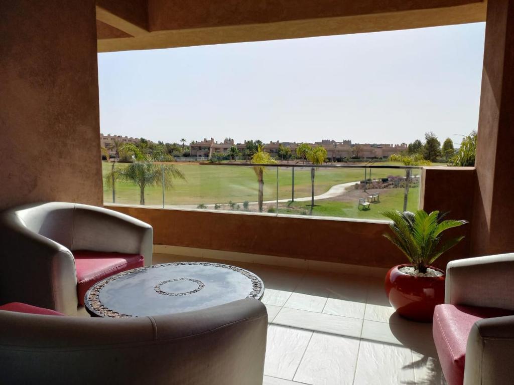 馬拉喀什的住宿－Corail Apart Golfique -Prestigia，客房设有桌椅和大窗户。
