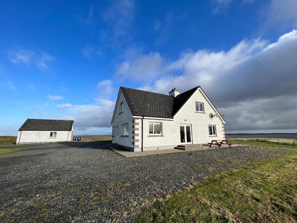 a white house sitting on top of a field at Airigh nam Fiadh in Clachan