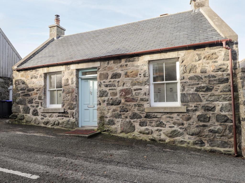 een stenen cottage met een blauwe deur en ramen bij 2 Seafield Place in Portsoy