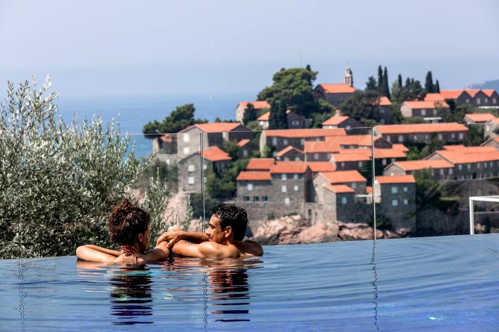 dos personas sentadas en el agua en una piscina en Villa Geba Boutique Hotel en Sveti Stefan