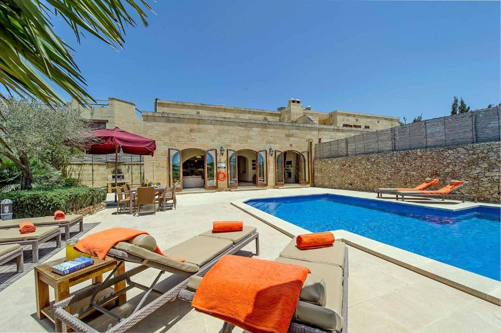 a swimming pool with chairs next to a building at The Olives Holiday Home in San Lawrenz